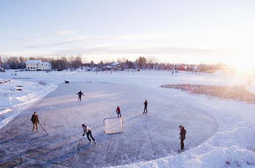 ice skating group of people playing outdoor hockey during winter game